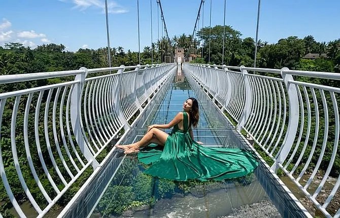 Woman posing on glass bridge walkway above the jungle in Bali